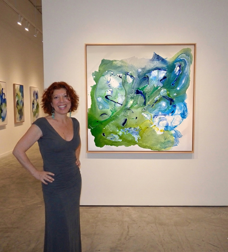 Artist standing next to 'Crystal Cove,' a large 48x48 inch square abstract painting featuring coastal-inspired textures and colors.