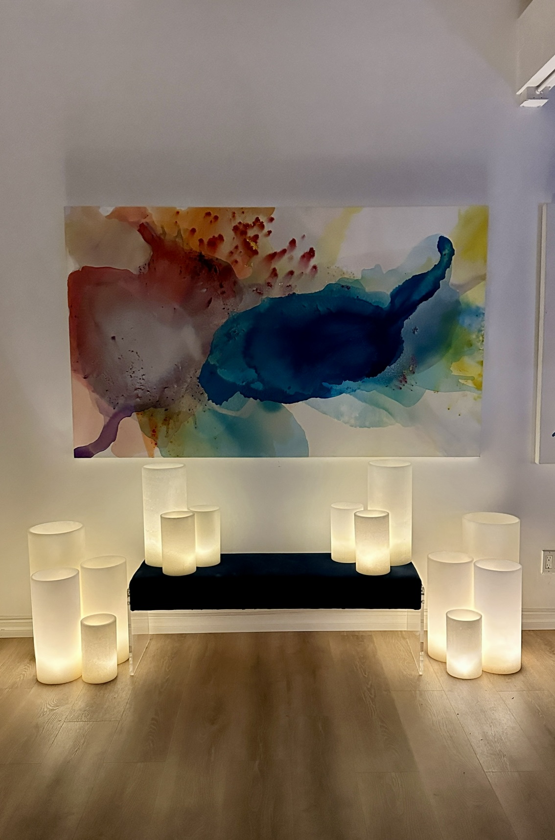 Inside Clara Berta’s abstract art studio in Laguna Beach, featuring the large-scale abstract painting 'Expansive Light' (48 x 78 in) displayed next to glowing LED wax candles.
