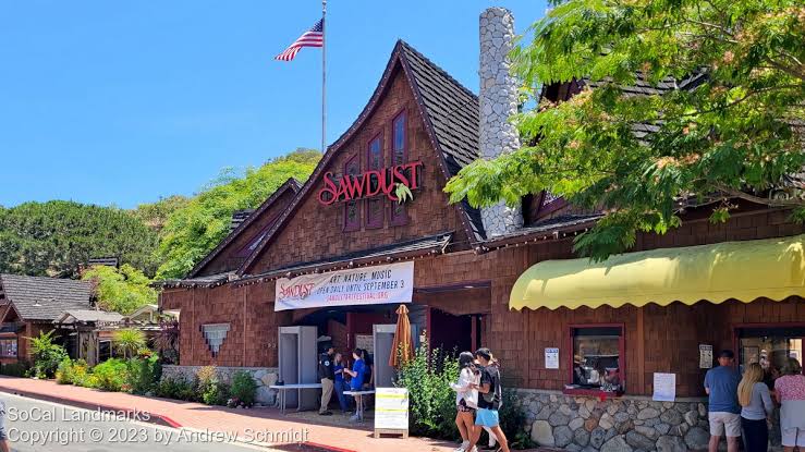 Visitors browsing handcrafted art and colorful displays inside the rustic wooden stalls at the Sawdust Art Festival.