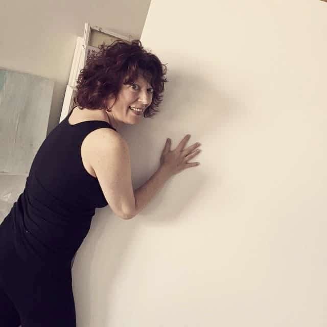 Clara Berta working on a large scale canvas during the creative process of abstract art in her studio space.