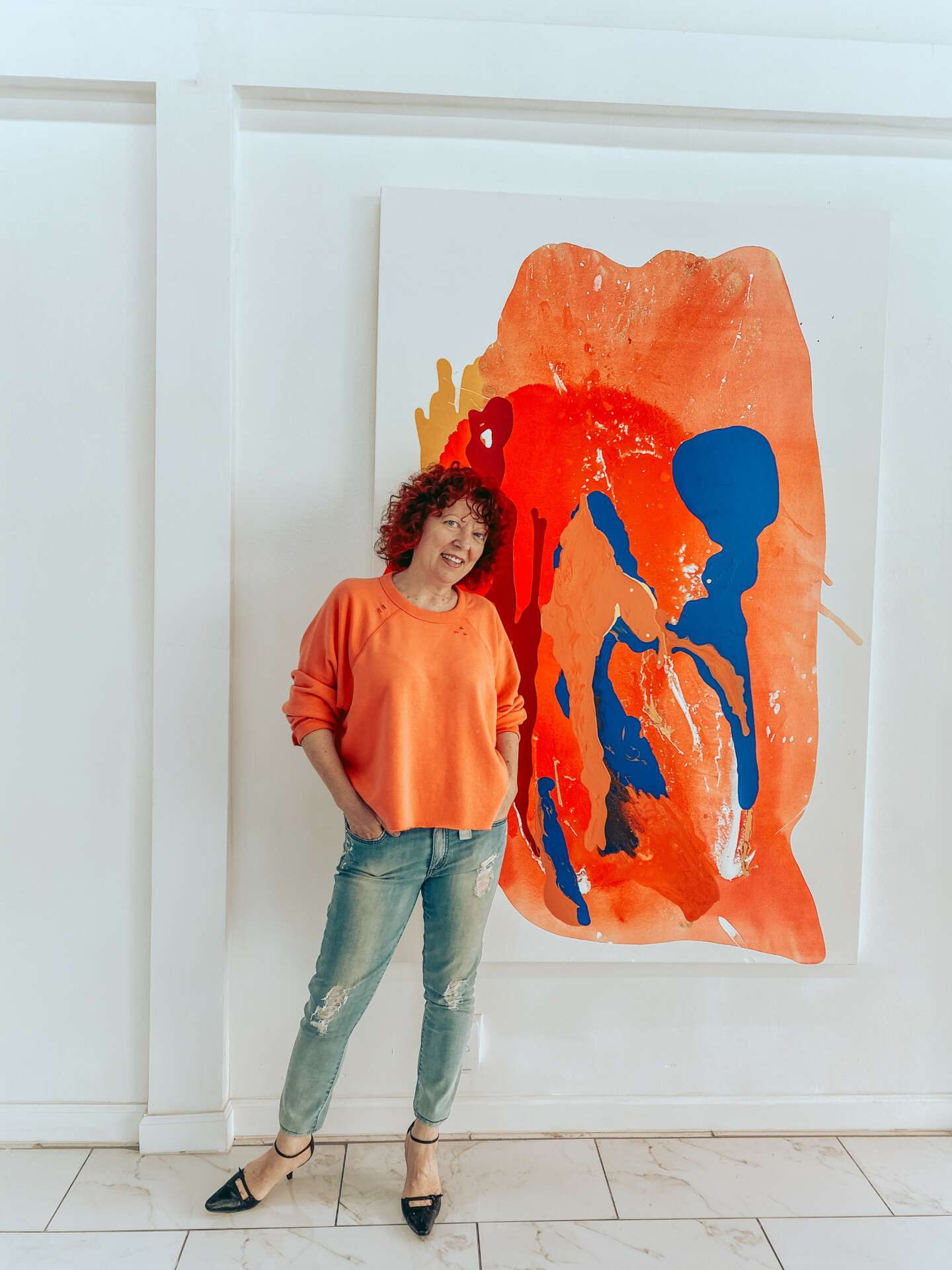 Artist Clara Berta in her studio standing next to a large-scale abstract painting for a commercial space.