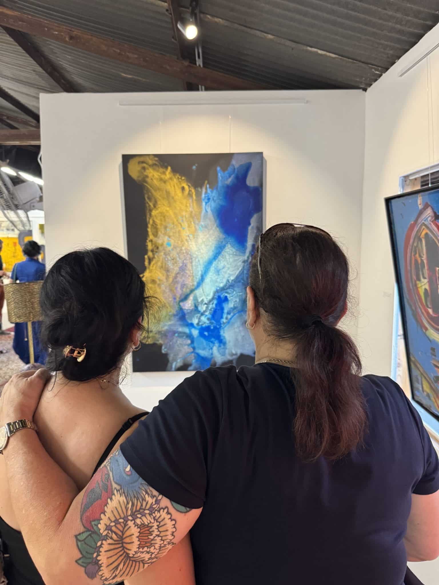 Collectors viewing Clara Berta modern abstract art painting Golden View at gallery opening.