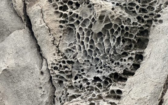 Close-up of rugged, porous volcanic rock and weathered terrain along the Pe’ahi (Jaws) hiking trail in Maui, showing the 